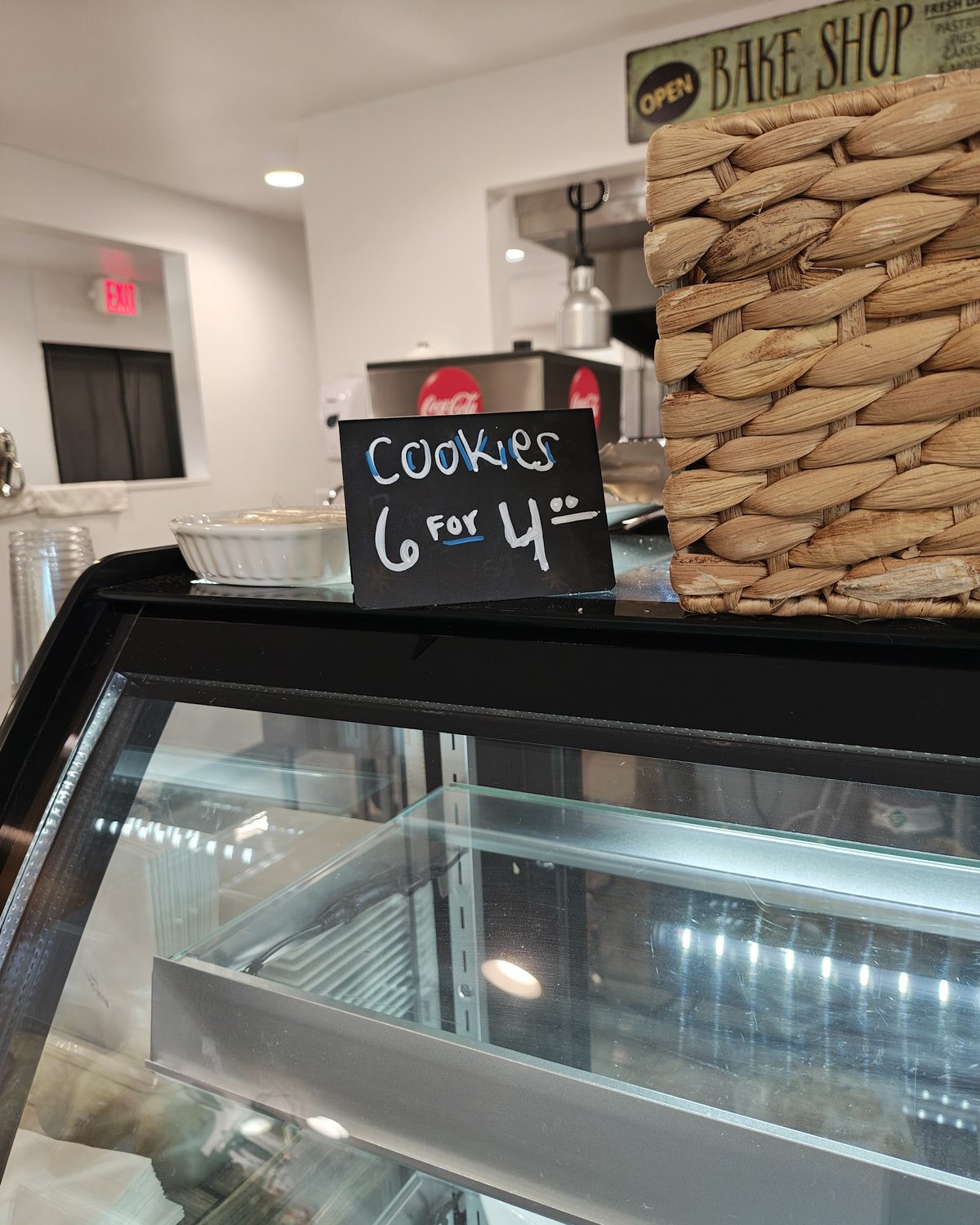 The bakery case under a Bake Shop sign, with a chalkboard reading Cookies 6 for 4