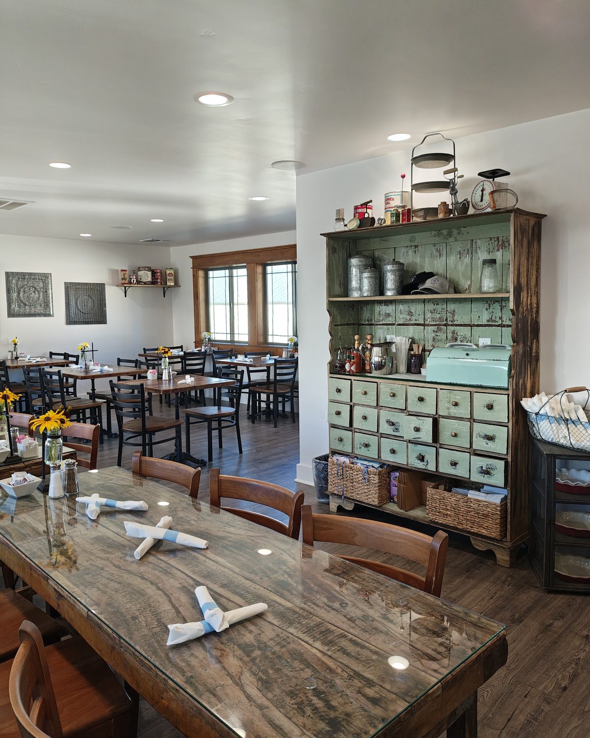 A long communal table set with napkins and small vases of flowers