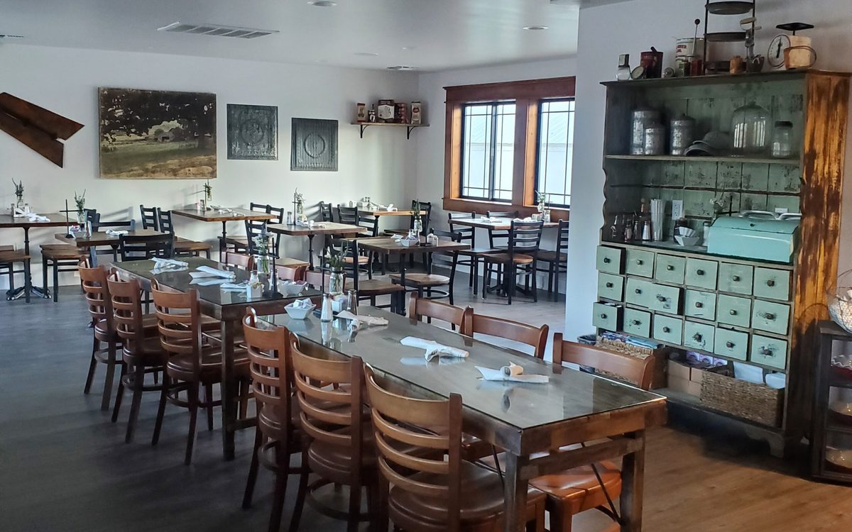 The dining room: long communal tables, wooden chairs and a mint-green apothecary cabinet