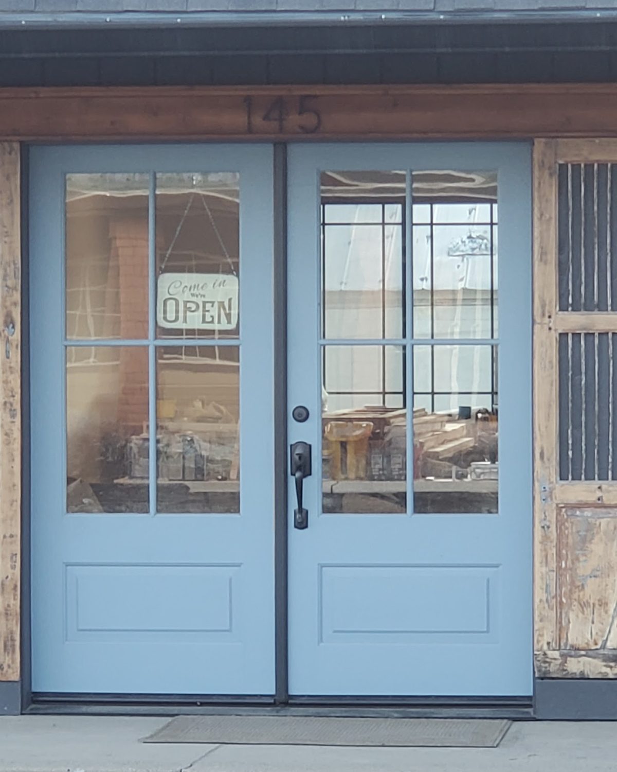 The blue front door at 145, with an Open sign hanging in the glass