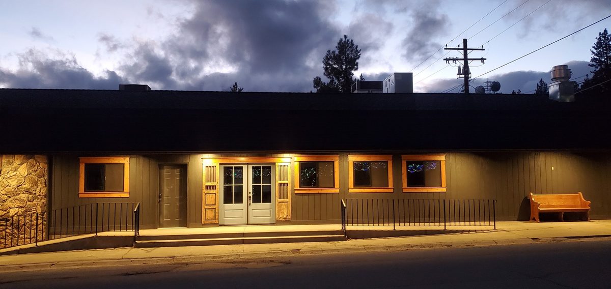 The cafe from across the street at dusk, windows lit warm against a dark sky