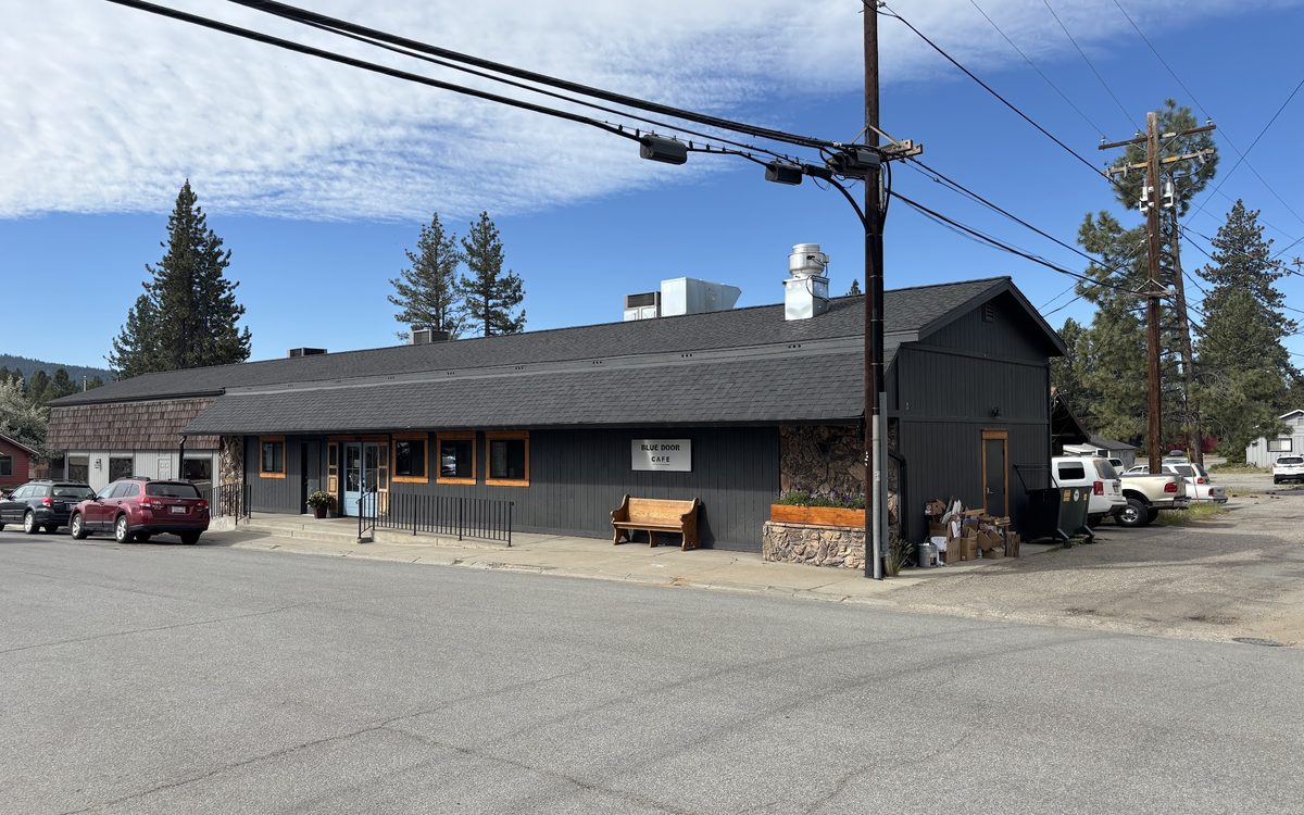 The cafe building seen from Pine Street on a clear day, pines and parked cars nearby